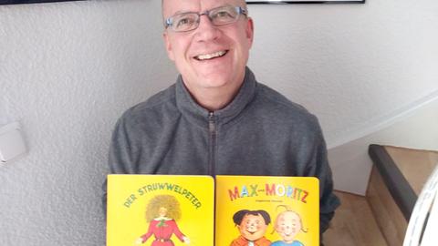 Hermann Hillebrand mit dem Büchern "Struwwelpeter" und "Max und Moritz"