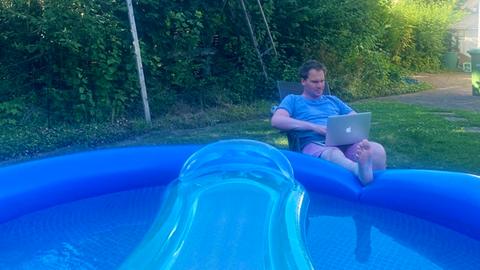 Jascha Küllmer mit Laptop am gefüllten, aufgeblasenen Pool.