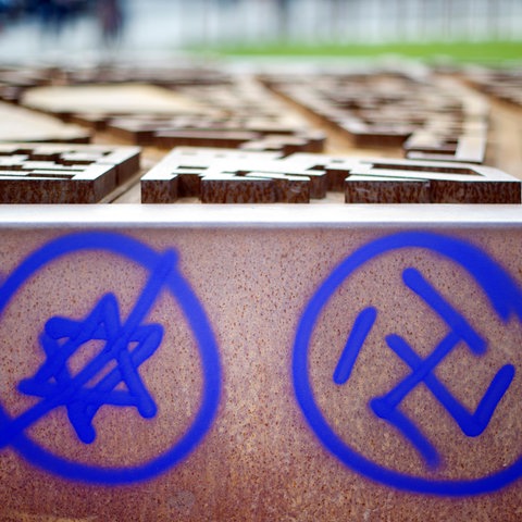 Ein Hakenkreuz und ein durchgestrichener Davidstern sind an einer Gedenkstätte in Berlin zu sehen.