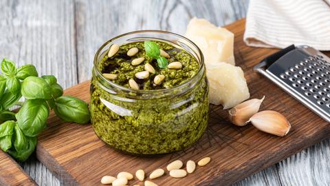 Pesto im Glas und die Zutaten Basilikum, Parmesan, Pinienkerne und Knoblauch