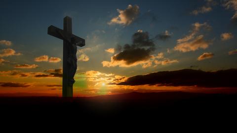 Geschnitzter Jesus am Kreuz auf einem Berggipfel im Sonnenuntergang