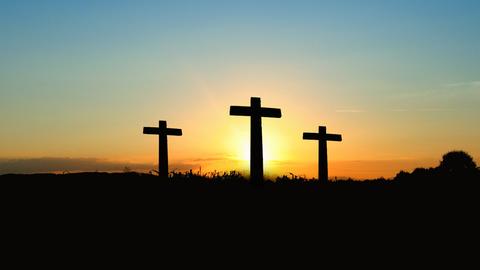 Drei leere Kreuze im Sonnenuntergang