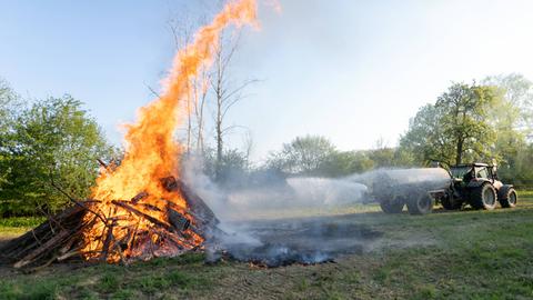 Ein Landwirt spritzt aus einem Güllefass Wasser auf ein Feuer