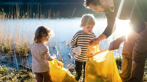 Vater sammelt mit zwei Kindern Müll