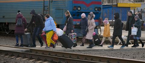 Menschen überqueren mit ihrem Gepäck die Gleise in Kramatorsk in der Region Donezk in der Ostukraine, um einen Zug nach Kiew zu nehmen. Russische Truppen haben ihren erwarteten Angriff auf die Ukraine gestartet.