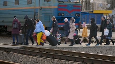 Menschen überqueren mit ihrem Gepäck die Gleise in Kramatorsk in der Region Donezk in der Ostukraine, um einen Zug nach Kiew zu nehmen. Russische Truppen haben ihren erwarteten Angriff auf die Ukraine gestartet.
