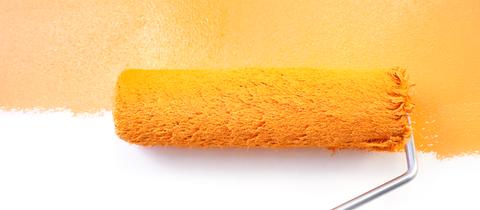 Weiße Wand wird mit oranger Farbe gewalzt
