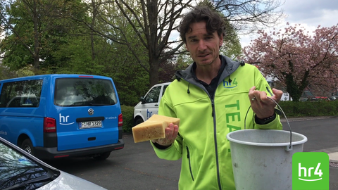 Uwe Becker beim Entfernen von Vogelkot auf der Motorhaube eines Autos